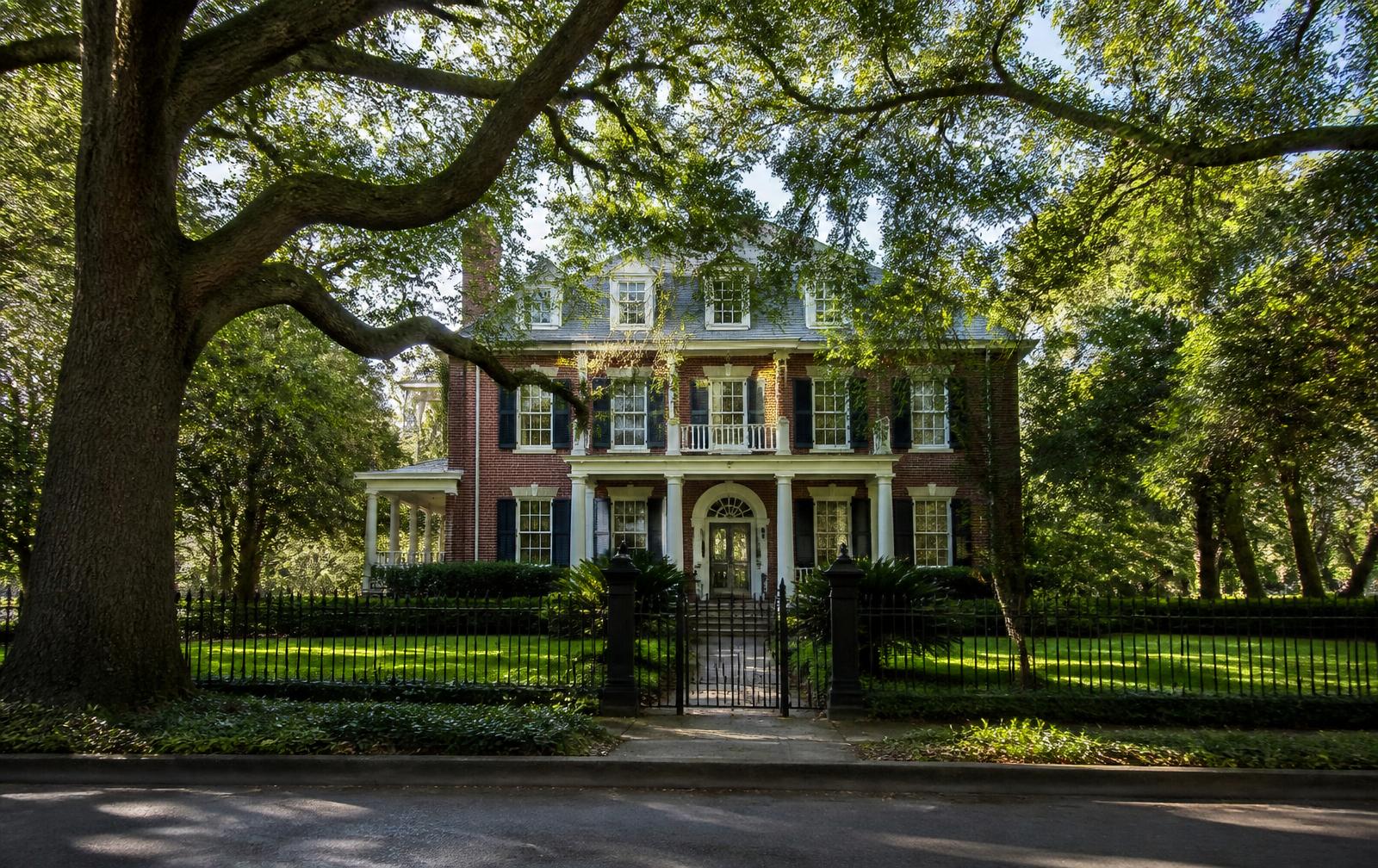 A red-brick Colonial Revival home behind an iron fence in Eastover, Charlotte
