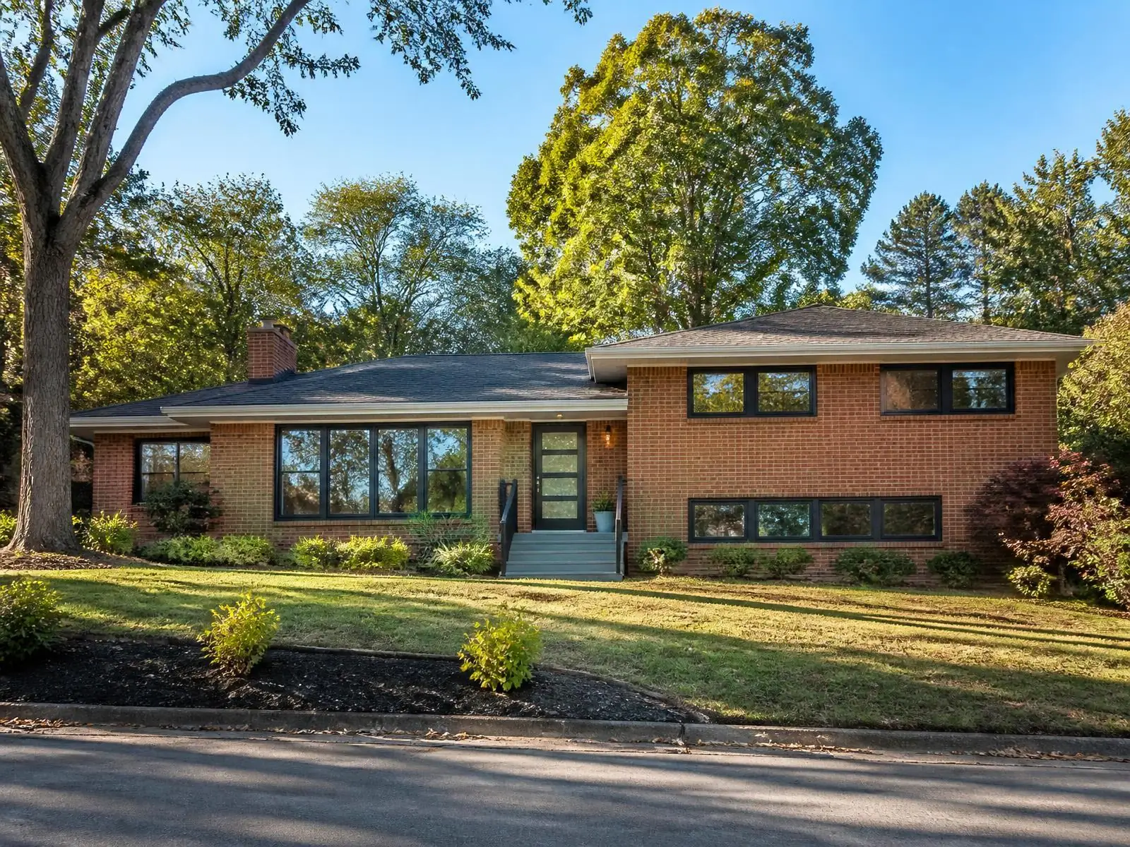 Renovated 1960s brick split-level home with black windows in an established Charlotte neighborhood