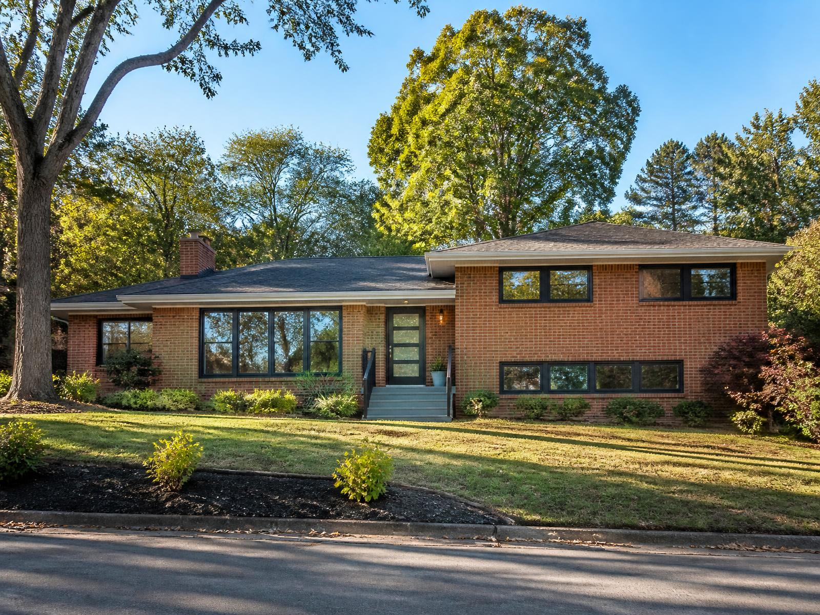 Renovated 1960s brick split-level home with black windows in an established Charlotte neighborhood