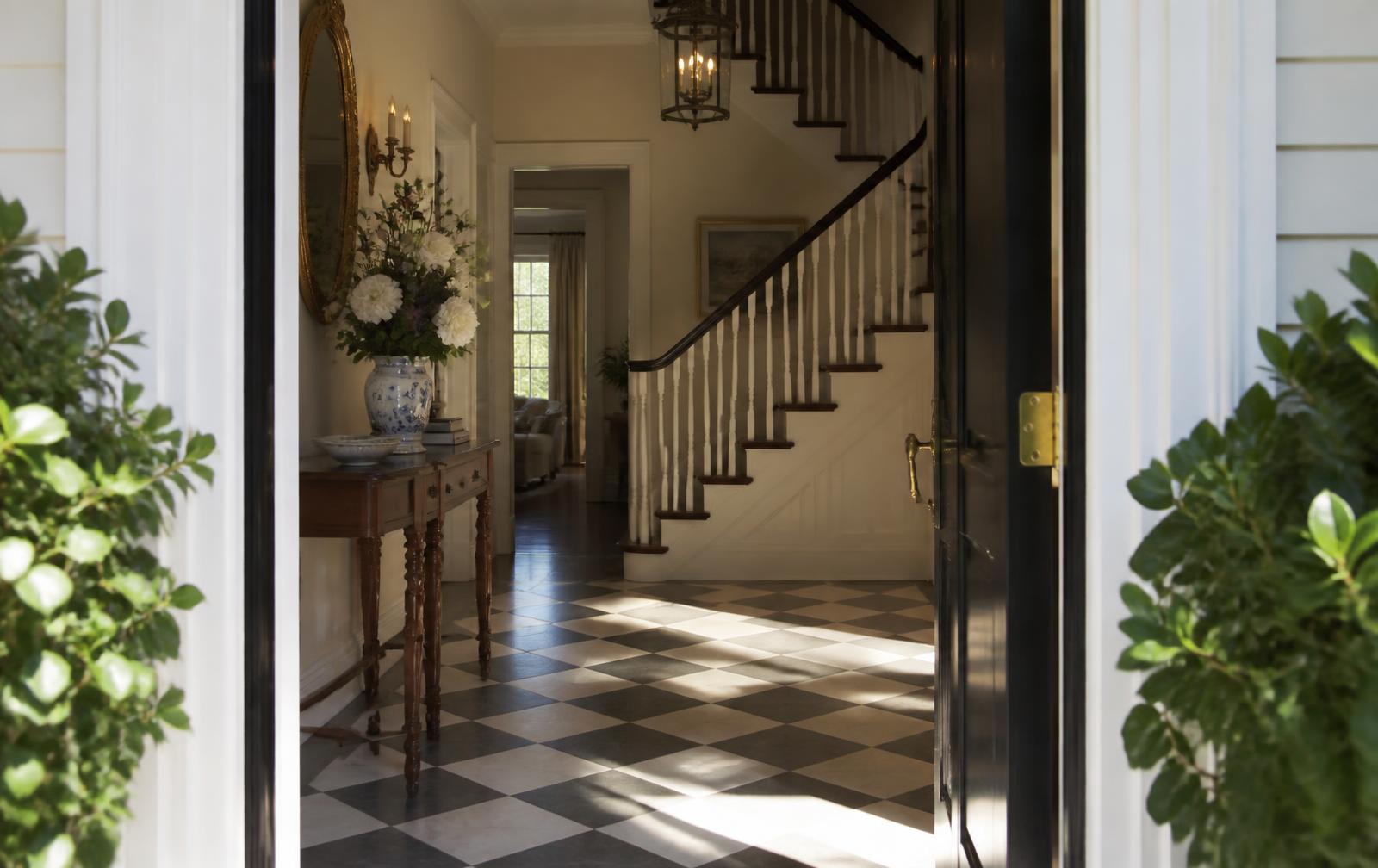 Sunlit entry hall with marble floor seen through an open front door